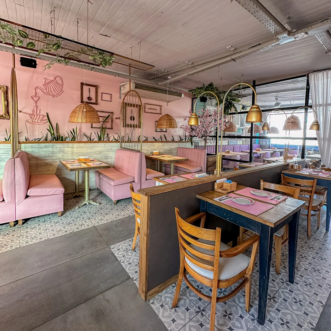 Salón con sillones rosas y mesas de madera