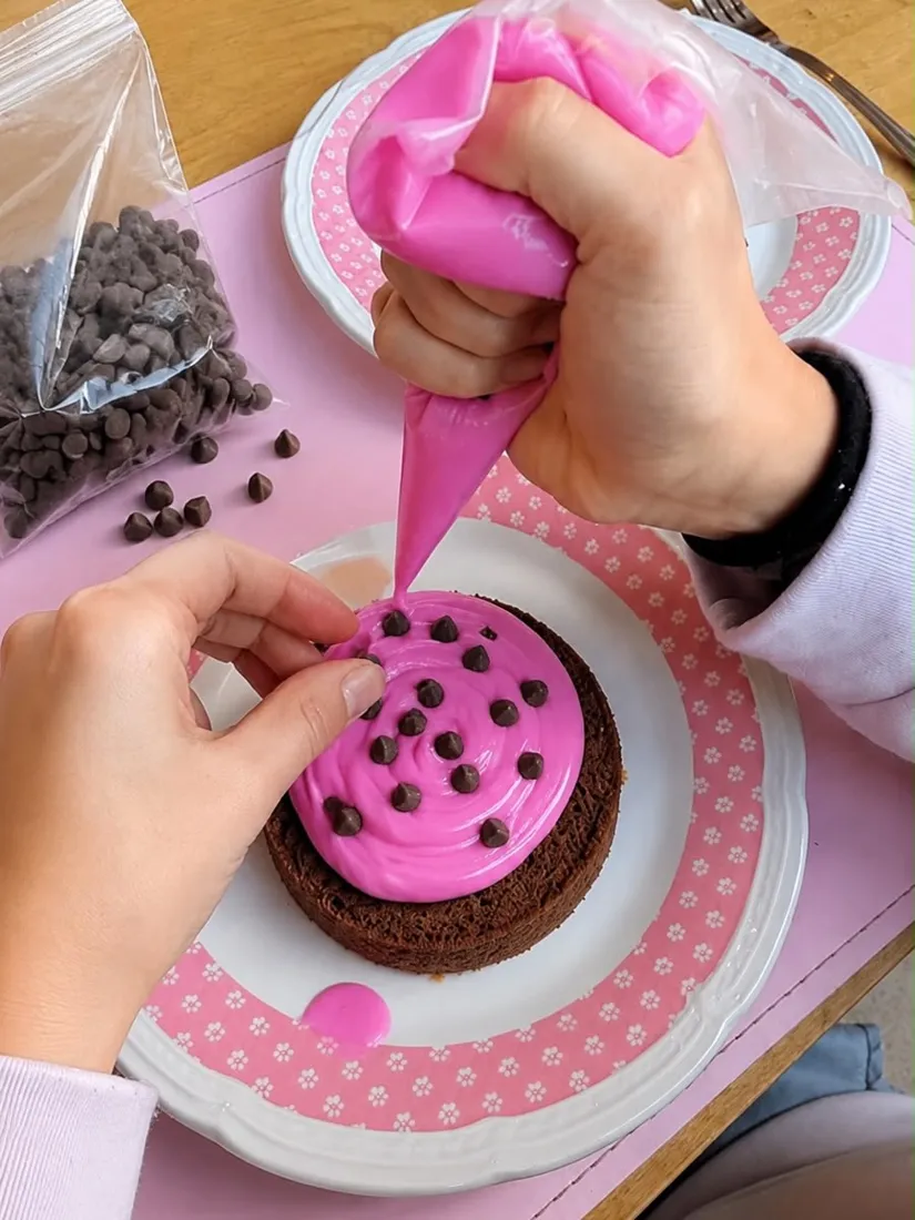 Chico decorando una torta con glasé rosa
